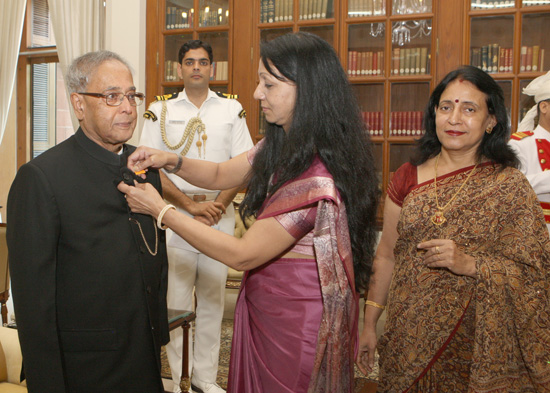 Smt. Rekha Gupta and others from CPWD Officers’ Wives Association pinning a flag on the President of India, Shri Pranab Mukherjee at Rashtrapati Bhavan in New Delhi on April 2, 2013 on the occasion of their Association on CPWD Employees Welfare Month.