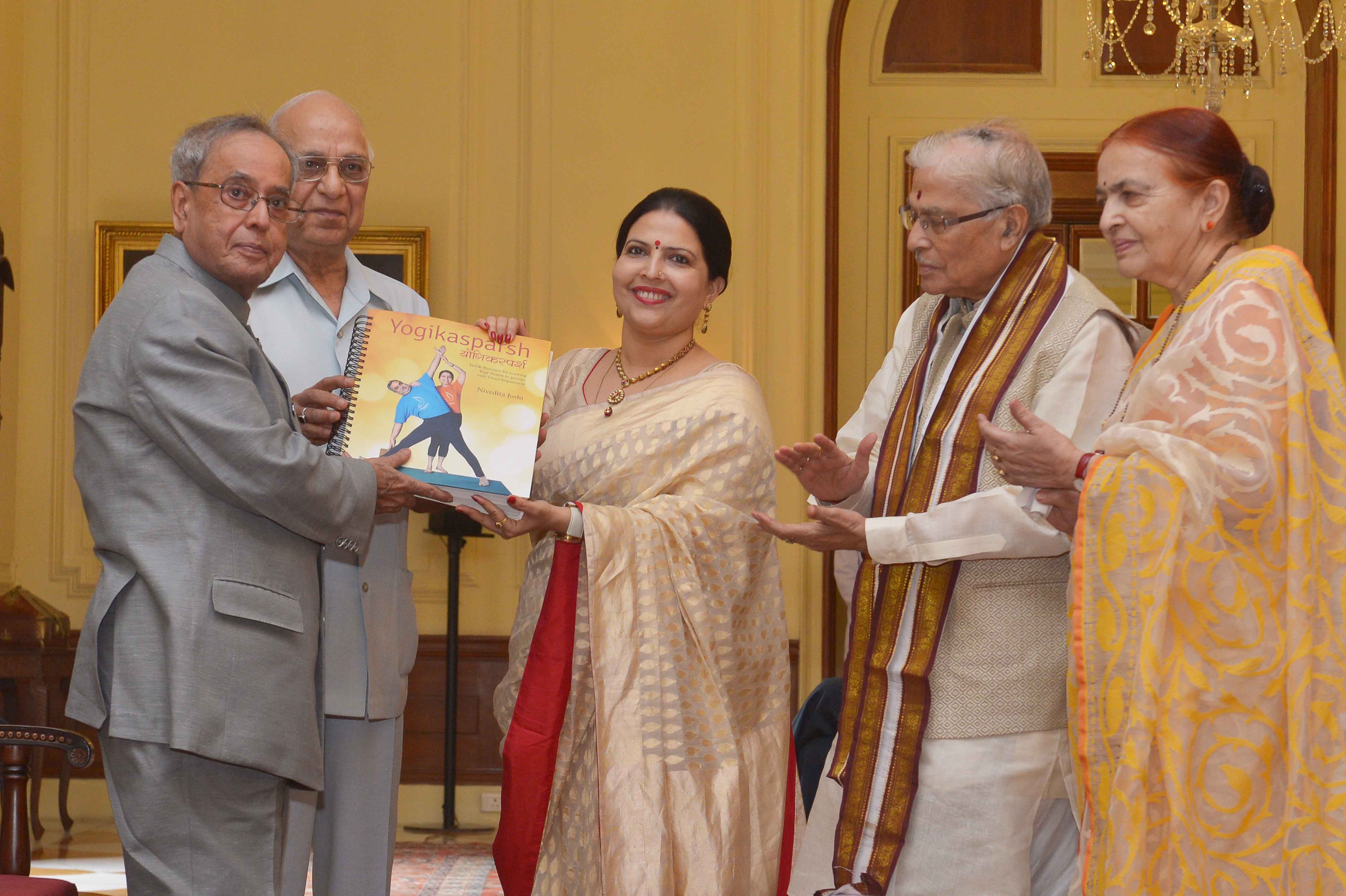 भारत के राष्ट्रपति, श्री प्रणब मुखर्जी 8 जून, 2015 को राष्ट्रपति भवन में श्रीमती निवेदिता जोशी द्वारा लिखित योगिकास्पर्श नामक ब्रेल योग पुस्तिका की प्रथम प्रति श्री सुभाष कश्यप, पूर्व महासचिव, लोकसभा से प्राप्त करते हुए।