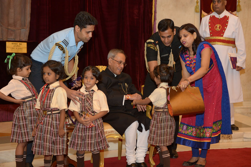 Children tying 'Rakhi' on the President of India, Shri Pranab Mukherjee at Rashtrapati Bhavan on August 10, 2014 on the occasion of Raksha Bandhan. 