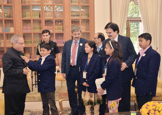 Children pinning a flag on the President of India, Shri Pranab Mukherjee at Rashtrapati Bhavan in New Delhi on November 23, 2012 on the occasion of their Flag Week when group of childrens and Secretary from the National Foundation for Communal Harmony ca